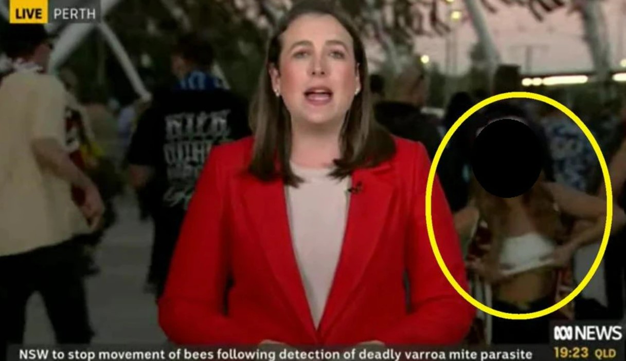 Female  State of Origin fan flashes the camera while reporter does a live cross